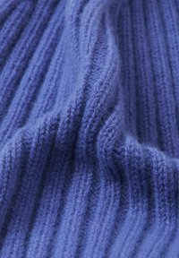 Tessuto a maglia rigata di un ricco colore viola, con una morbida e soffice texture. Il design presenta linee verticali che creano profondità e dimensione.