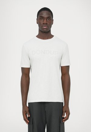 Bela kratka majica s kratkimi rokavi iz teksturirane tkanine; na prsih se nahaja subtilen napis "DONDUD" v mehki sivi barvi.