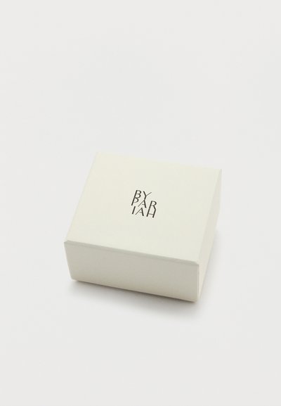 Négyzet alakú, texturált, krémszínű doboz, tetején sötét betűkkel dombornyomott "BY PARIAH" logóval. Tiszta dizájn, minimalista esztétika.