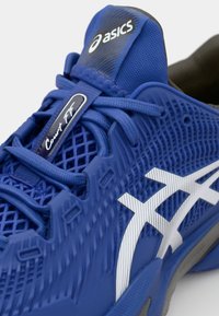 Chaussure de sport bleue avec tige en maille, détails texturés, marquage blanc et lacets. Notable pour son design respirant et ses accents de rembourrage.