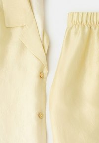 Helles gelbes, strukturiertes Stoffblazer mit Revers und zwei Knöpfen, kombiniert mit passenden Hosen mit elastischem Bund.