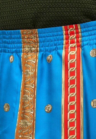 Σορτσάκι με ελαστική μέση από μπλε ύφασμα, κατακόρυφες διακοσμητικές πορτοκαλί και κόκκινες ρίγες με περίπλοκα χρυσά σχέδια και κυκλικά χρυσά μοτίβα.