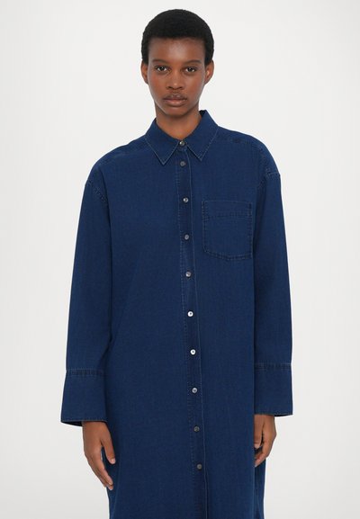 Mørkeblå denim skjortekjole med knaplukning foran, spids krave, lange ærmer og en brystlomme. Glat tekstur og afslappet pasform.
