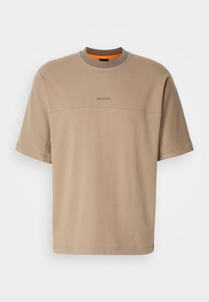 Beige T-shirt met een ronde hals en korte mouwen, met een gestructureerd bovenpaneel en een subtiele logo op de voorkant. Aangevuld met een oranje accent rond de hals.