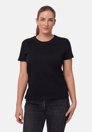 Svart kortärmad t-shirt i bomull med rund halsringning och avslappnad passform, bärs med mörkgrå jeans.