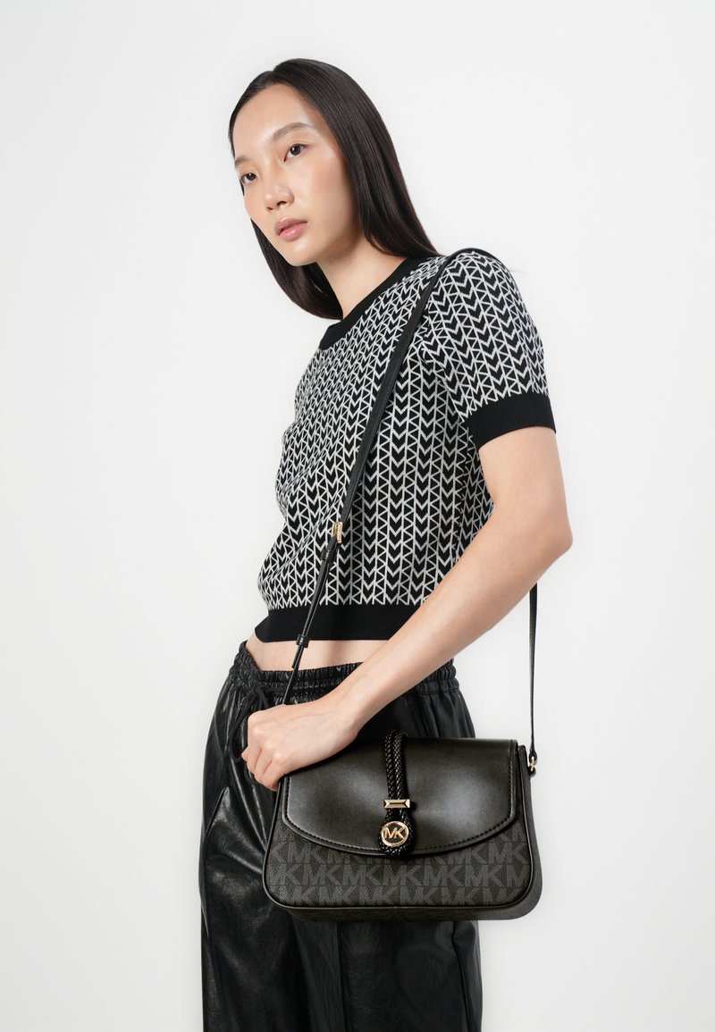 Schwarze Lederhandtasche mit einem gepolsterten Stoffpanel, das ein Monogrammmuster aufweist. Die Tasche ist mit einem geflochtenen Griff und goldenen Hardware-Elementen versehen.