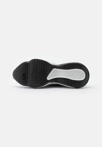 Svart och vit idrottssko sula, med en texturerad yta som har spår och en distinkt Nike-logotyp nära hälen.