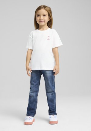 Witte katoenen t-shirt met korte mouwen, roze logo op de borst, gecombineerd met blauwe spijkerbroek en meerkleurige platform schoenen.