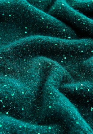 Türaqua Stoff mit weicher Textur und verstreuten kleinen, glänzenden Pailletten, die einen schimmernden Effekt auf der gefalteten Fläche erzeugen.