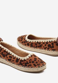 Chaussures plates à imprimé léopard brun avec une tige en daim texturé, un bord en zigzag et des détails en corde de jute le long de la semelle.