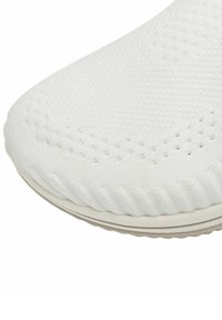 Tige de chaussure de sport blanche, en matériau tricoté texturé avec des perforations, de forme arrondie et avec une semelle légèrement rembourrée.