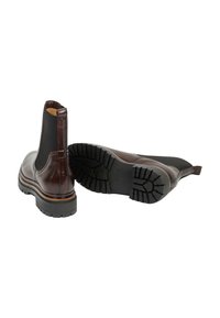 Bottes Chelsea en cuir marron foncé avec des panneaux latéraux élastiques noirs et des semelles épaisses en caoutchouc noir, une droite et une montrant le motif de la semelle.