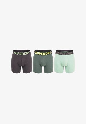 Drie paar herenshortjes in donkergrijs, groen en licht muntkleur met zwarte taillebanden met "SUPERDRY" in grote letters.