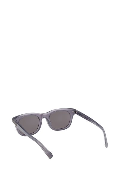 Harmaat läpikuultavat aurinkolasit, joissa tummat linssit. Kulmikas kissansilmämuoto, ohuttemppeliset, joissa teksturoidut korostukset. Kevyt muovimateriaali.