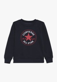 Felpa blu navy con un grande logo rotondo rosso e bianco di Converse All Star al centro. Polsini e colletto a coste per un tocco di texture in più.
