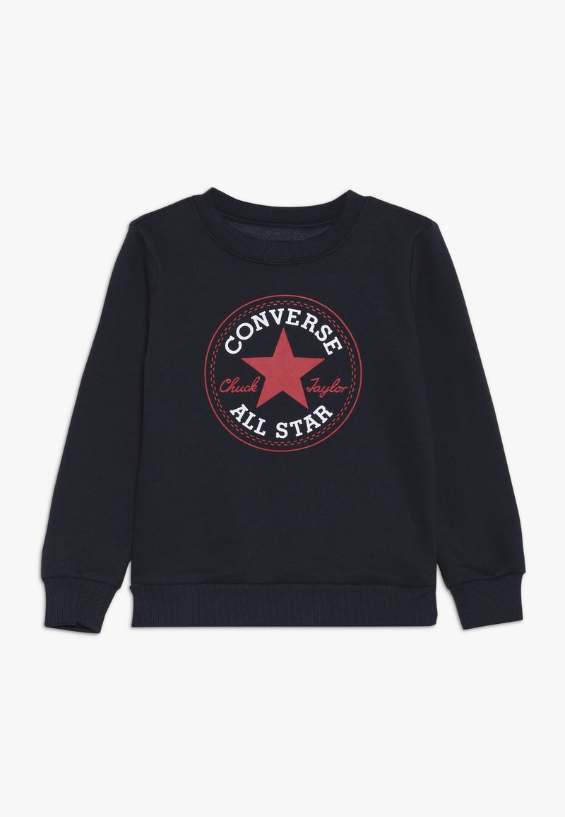 Felpa blu navy con un grande logo rotondo rosso e bianco di Converse All Star al centro. Polsini e colletto a coste per un tocco di texture in più.