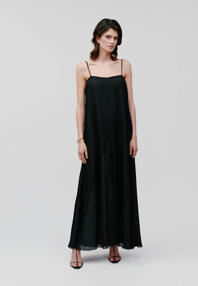 Black pleated maxi dress with thin spaghetti straps. Lightweight fabric with a flowing silhouette and subtle textured pattern.