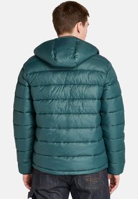 Pohodlná pánská bunda z modré látky s kapucí, která se vyznačuje prošívaným designem a lesklou texturou. Zadní strana obsahuje rovný lem a elastické manžety.