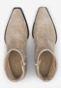 Beżowe zamszowe botki za kostkę z ostro czubkiem, bocznymi zamkami błyskawicznymi i gładką podszewką. Posiadają czarną, nieco podniesioną podeszwę.