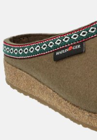 Brun filtsandal med en korksål, der har et grøn, rød og hvid mønstret tekstilbånd og et sort Haflinger-label.
