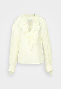 Pale yellow långärmad blus med volang vid V-halsen och breda manschetter, visad mot en vit bakgrund.