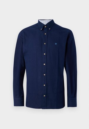 Camicia di cotone blu navy con colletto button-down, bottoni marroni e motivo a scacchi all'interno del colletto. Presenta un logo ricamato discreto.