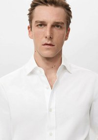 Biała koszula na guziki wykonana z gładkiej tkaniny, z klasycznym kołnierzem i subtelnym połyskiem, o standardowym kroju i minimalistycznym wzornictwie.