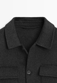 Donkergrijze wollen jas met een kraag, twee borstzakken en een enkele knoopsluiting; zachte textuur en minimalistisch ontwerp.