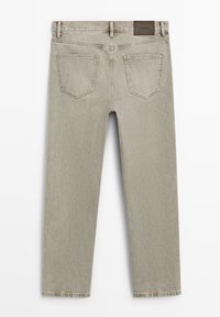 Achteraanzicht van beige denim jeans met twee achterzakken, riemlussen en een bruine lederen merkembleem op de tailleband.