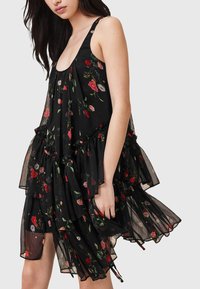 Schwarzes Kleid mit floralen Mustern aus schicht transparentem Stoff, mit roten und pinken Blumenmustern, Rüschendetails und einem runden Ausschnitt.