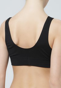 Svart sportbehå med breda axelband och design med rundad rygg. Tillverkad av ett glatt, stretchigt material för komfort. Inga synliga fästen eller sömmar.