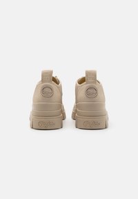 Baskets à plateforme beige avec une finition en cuir texturé, présentant une marque en relief sur le talon et la languette. Forme arrondie, design minimaliste.