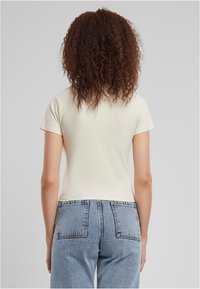 Ljusgul tajt t-shirt med korta ärmar, slät textur och rund halsringning, kombinerad med högmidjade blå denimjeans.