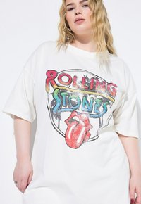 Hvid oversized t-shirt med et multifarvet "Rolling Stones" grafisk design og logo med røde læber. Blødt stof, korte ærmer, afslappet pasform.