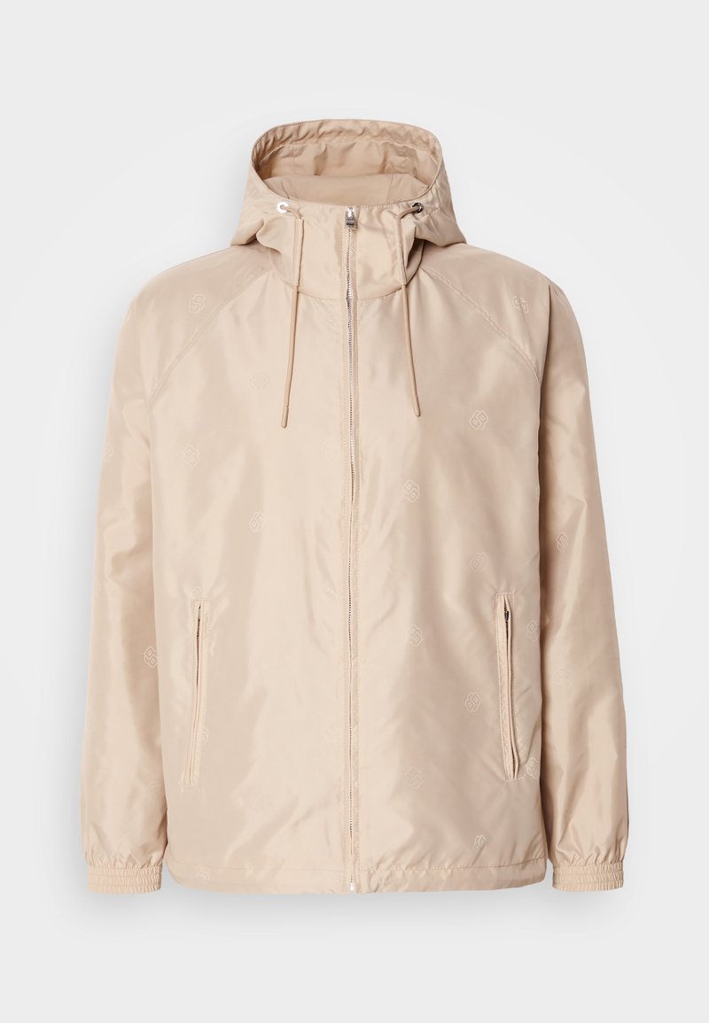Veste légère beige avec une capuche, dotée d'une fermeture éclair intégrale, de deux poches latérales, de poignets élastiques et d'un subtil motif de logo en relief.