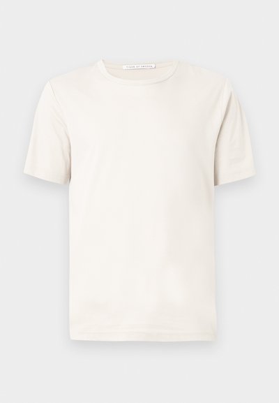 Απλή λευκή κοντομάνικη μπλούζα με στρογγυλή λαιμόκοψη και ετικέτα "Tiger of Sweden" στο γιακά, σε φωτεινό γκρι φόντο.