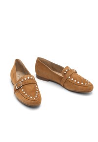 Tan suede loafers with smooth texture, rounded toe, and decorative silver studs along the upper. Low, flat heel. Buckle accent on the strap.