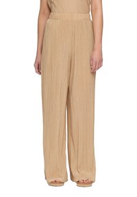 Helle beigefarbene, plissierte weite Hosen mit elastischem Bund und weicher Textur, die eine entspannte Passform aufweisen und elegant fallen.