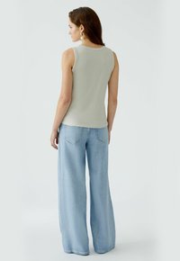 Light gray sleeveless top with a fitted design, paired with light blue wide-leg denim jeans, featuring back pockets and a clean finish.