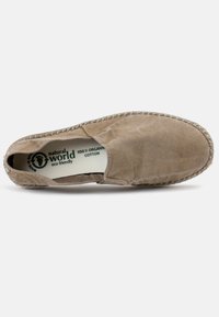 Beige színű, organikus pamut, slip-on cipő szőtt jutaszolettal, rugalmas oldalsó panelekkel és diszkrét textúrával a felső részen. Környezetbarát márkajelzés belül.