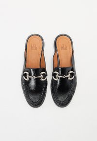 Black patent leather slip-on shoes with a leather interior, featuring a silver chain accent on the vamp and a round toe shape.