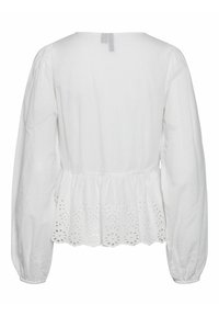 Blusa bianca con maniche lunghe a sbuffo, scollatura rotonda e orlo a peplo con dettagli a occhio di pernice. Realizzata in cotone morbido.