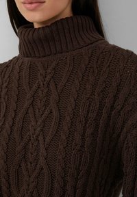 Schokoladenbrauner, kabelgestrickter Rollkragenpullover mit prominentem, geripptem Kragen. Verfügt über strukturierte Muster, die dickes, weiches Garn präsentieren.