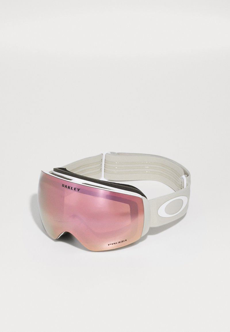 Oakley slidinėjimo akinius su dideliu, veidrodiniu rožiniu lęšiu, balta rėmeliu ir pilka reguliuojama juosta, aptrauktus putomis patogumui.