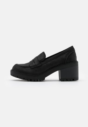 Czarny loafer z grubym obcasem, żłobioną podeszwą, pasek typu penny i teksturowaną cholewką, pokazany z profilu na białym tle.