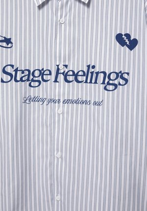 Bela srajca s tankimi navpičnimi črtami, modri napis 'Stage Feelings' in 'Letting your emotions out', ikoni razbitega srca in varnostne zatičnice.