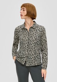 Long-sleeve shirt in black and cream floral print, featuring a collared neckline and button closure, made from soft, textured fabric.