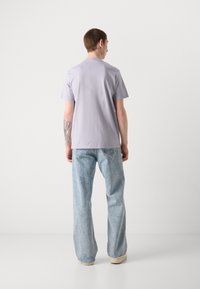 Light purple short-sleeve t-shirt with a relaxed fit, paired with light blue wide-leg jeans, featuring a subtle faded texture.