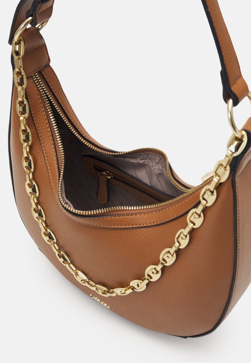 Sac à main en cuir marron avec détail chaîne dorée et fermeture éclair ouverte, montrant une doublure intérieure beige et une poche intérieure zippée.