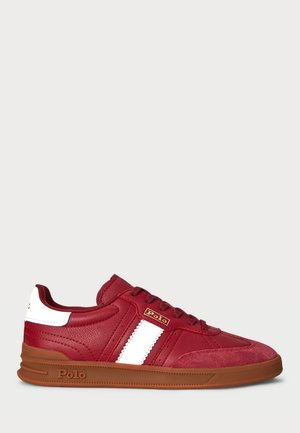 Rode leren sneaker met witte zijstreep, bruine rubberen zool, veters aan de voorkant en "Polo"-branding op de zijkant en hieltab.